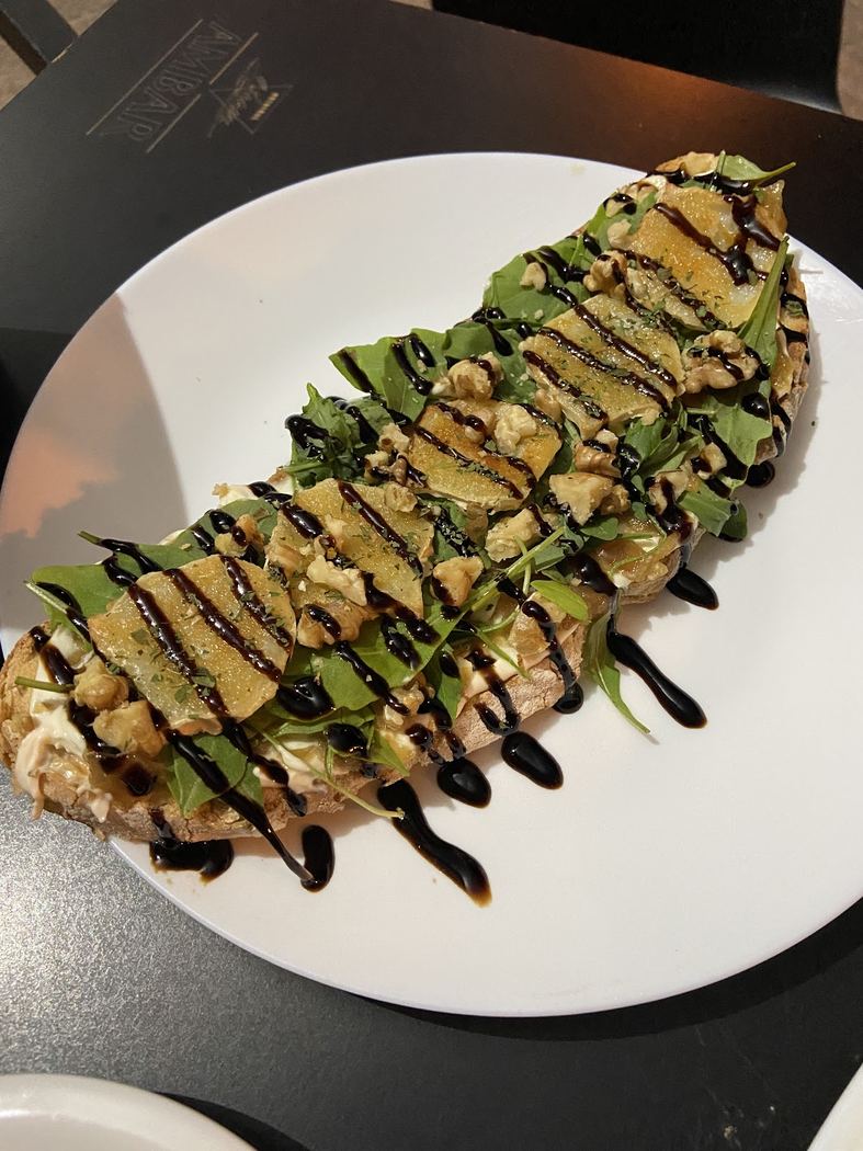 Tosta de rulo de cabra con nueces y rúcula, aliñada con reducción balsámica.